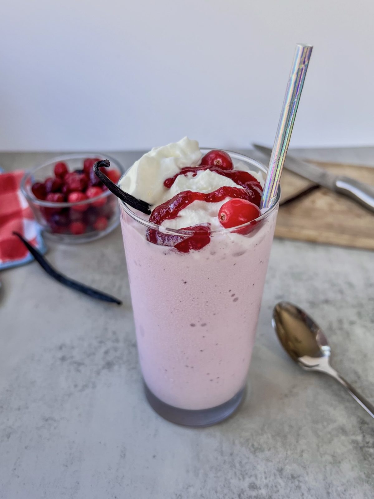 Cranberry vanilla bean milkshake with whipped cream, cranberry compote, and a vanilla bean on top.