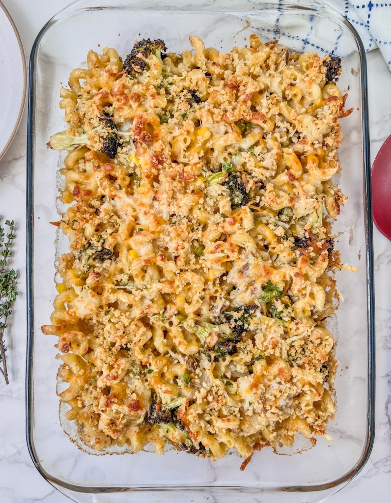 Creamy lemon cod pasta bake fresh out of the oven with some plates and a serving spoon nearby.