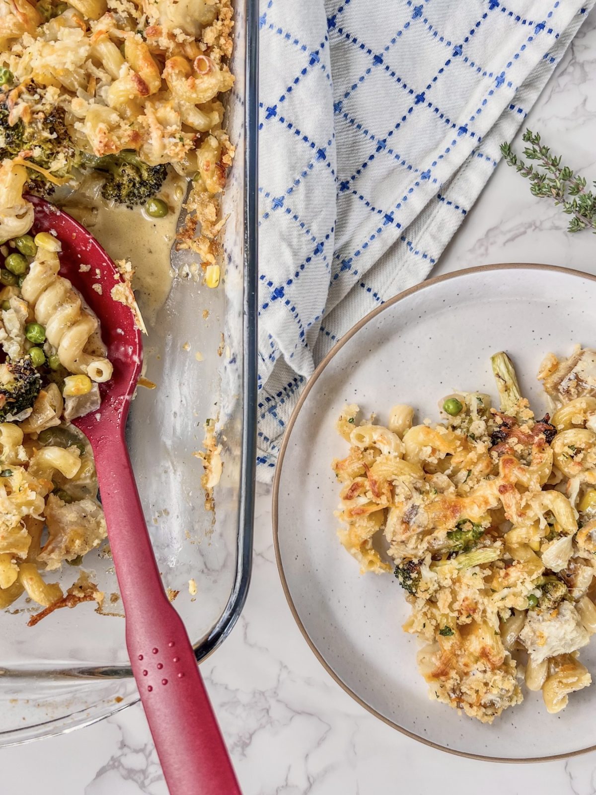 Creamy lemon cod pasta bake in a baking dish with some being scooped onto a plate.