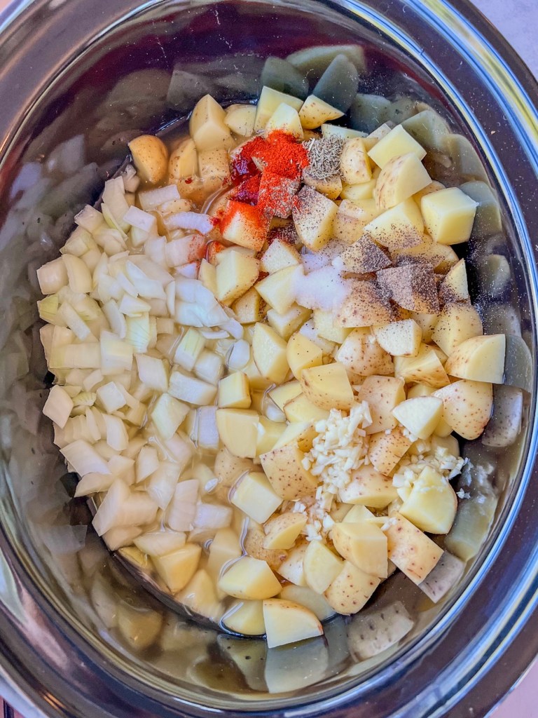Potatoes, onion, garlic, spices, and broth in a large crockpot.