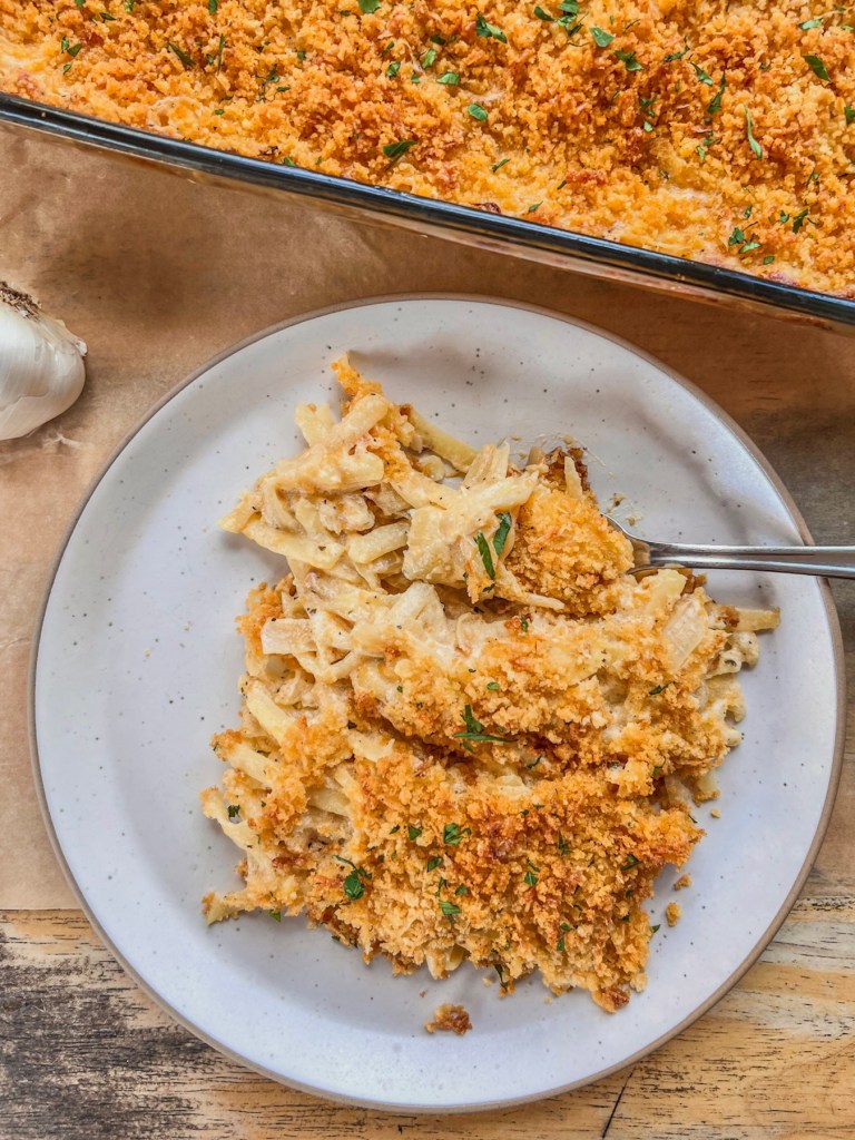 Roasted garlic cheesy potatoes on a plate with some fresh parsley on top.